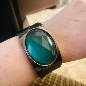 Relativity hinged cuff bracelets with large green stones.